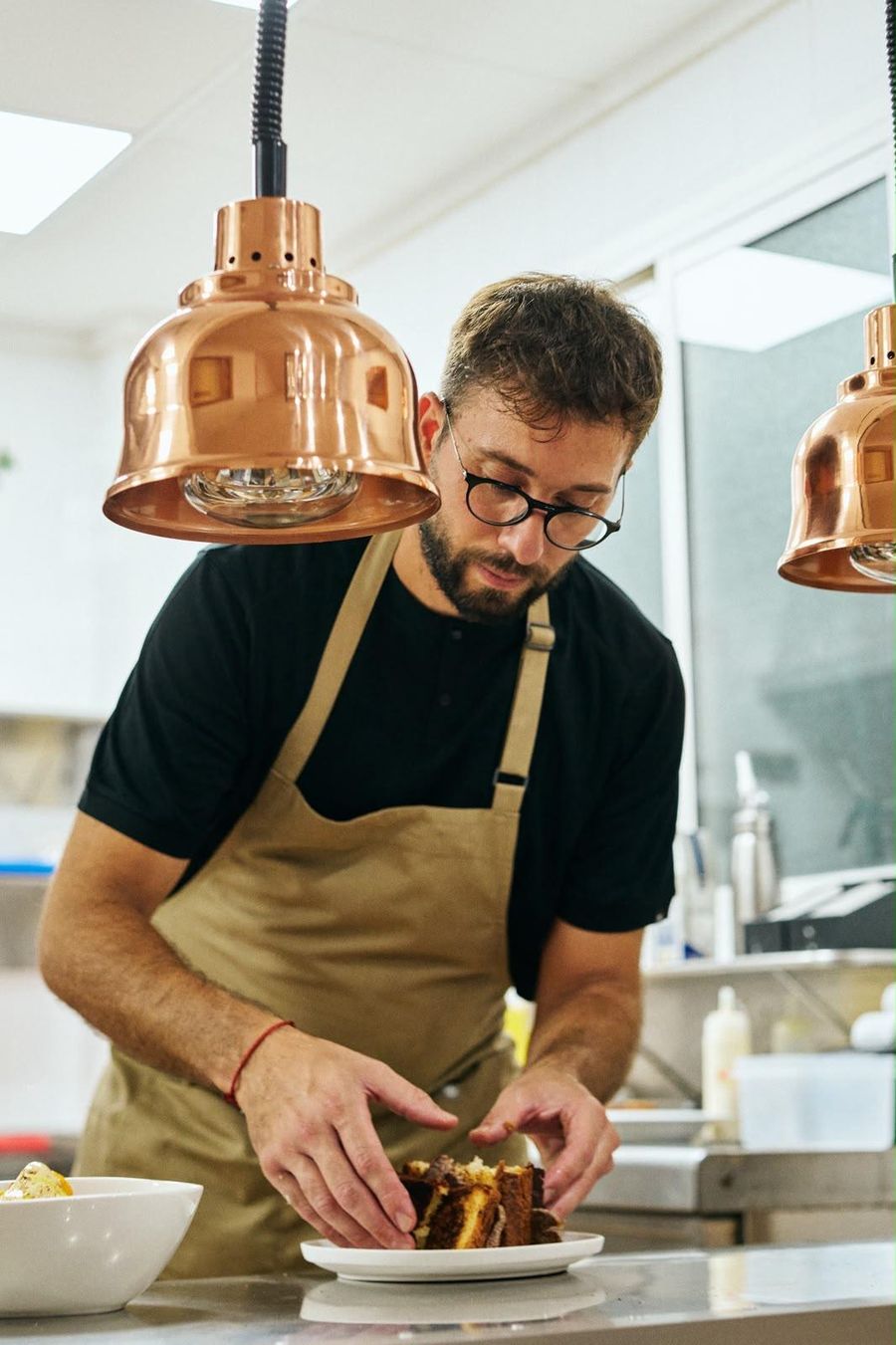 El chef Salva Baltasar emplatando un postre bajo lámparas de cobre